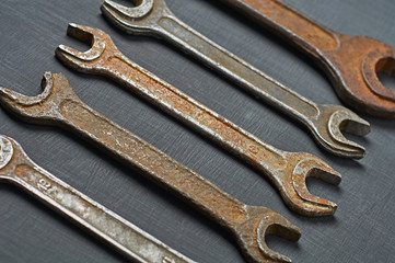 Row of old rusty and messy wrenches for nuts lies on dark concrete