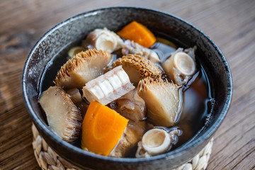 A bowl of Hericium erinaceus shark bone soup on a wooden table © Lili.Q
