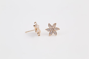 Gold earrings with diamond-shaped flowers on the white background.