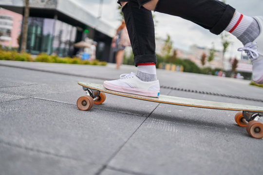 Image of legs of woman riding skateboard on street in city