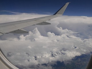 Fototapeta na wymiar Storm clouds seen from an airplane window, with an airplane wing in view.