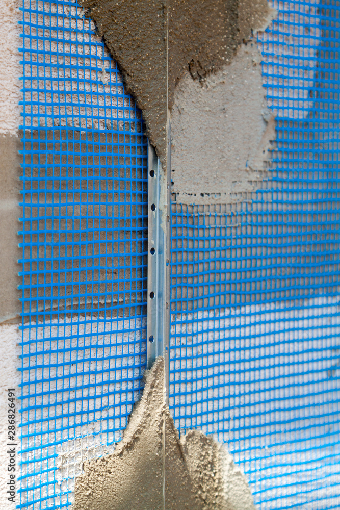 Poster surface of wall with applied construction grid and guides for plaster application