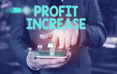 Conceptual hand writing showing Profit Increase. Concept meaning the growth in the amount of revenue gained from a business Male wear formal suit presenting presentation smart device