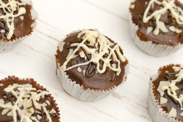 Five homemade chocolate cupcakes on white wooden table, high angle view