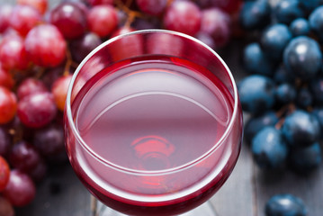 glass of red wine and grapes on black wooden table background