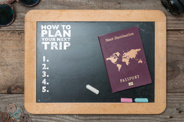 A chalkboard showing tips to plan a trip. Black chalkboard with sunglasses, lens and some coins...