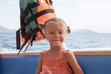 Fototapeta premium girl in orange dress with life jacket weighing behind her head takes walk on boat