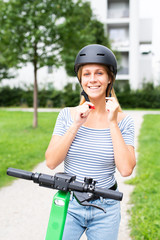 Junge Frau zieht einen Helm an um mit einem E-Scooter zu fahren 