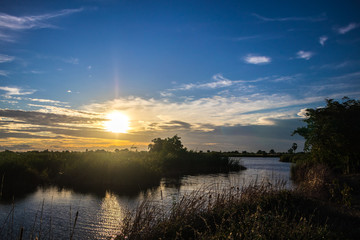 Picturesque scenery of the sunset on the lake in the evening with the clouds in dark blue sky background