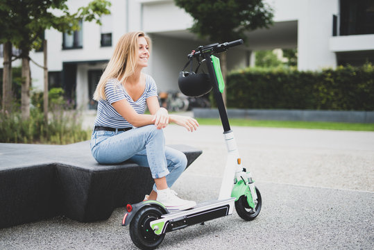 Freudig lachende junge Frau mit E-Scooter 