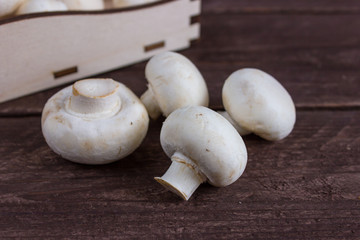 Champignon mushrooms in a wooden tray on a dark background