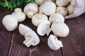 Champignon mushrooms in a bag on a dark background with a sprig of greenery