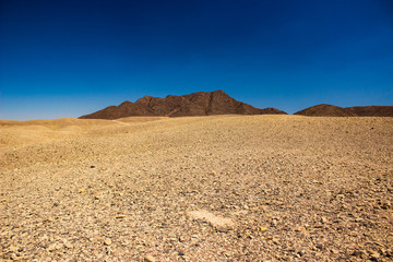 wilderness wasteland landscape global warming result dry dead ground to horizon and bare mountain with vivid blue sky background, copy space 