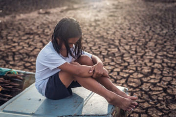 Sad Asian girl sitting on boat suffer from drought , Climate change from global warming.