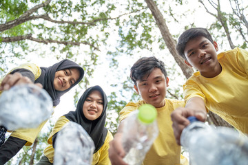 Group of asian teenage volunteers pick up bottle trash at the park