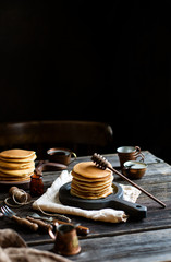 homemade two stacks of pancakes on wooden boards with pouring honey and honey stick