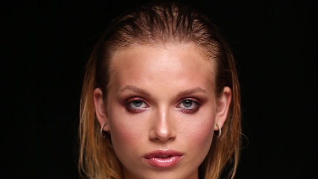 Close-up portrait of a girl on a black isolated background. Blonde with wet hair posing in the studio.