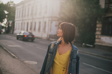 Beautiful woman in yellow jumpsuit posing on city streets.