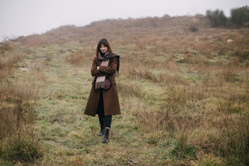 Woman in brown stylish cashmere posing on autumn background.