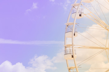 Ferris wheel on the colorful cloudy sky. Background concept of happy holidays time.
