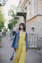 Fototapeta premium Woman in stylish yellow jumpsuit posing on city streets.