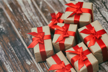 Some gift boxes wrapped in brown craft paper and tie red satin ribbon. Decorative wooden background. Your text space. Set of presents.