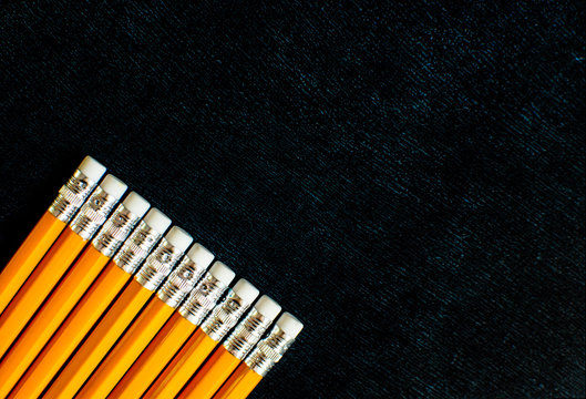 Lots of pencils on black slate background.