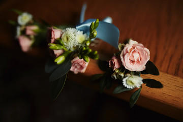 Stylish buttonhole, boutonniere for the groom. Wedding accessory on the table on wooden background. Flat lay. Top view.