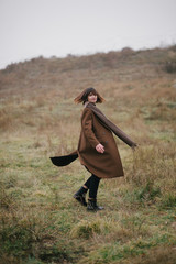 Woman in brown stylish cashmere posing on autumn background.