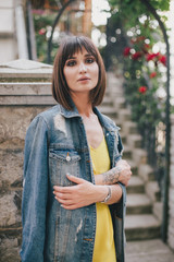 Beautiful woman in yellow jumpsuit posing on city streets.