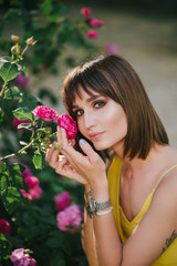 Woman beauty with tattoo on hand near roses in garden.