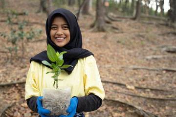 Hijab woman with new trees volunteering in park