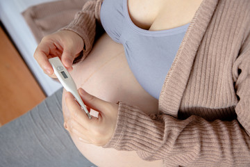 young pregnant woman hold  digital thermometer.