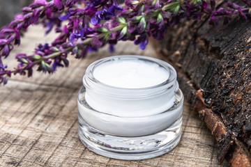 Natural face cream with blue lavender wildflowers on a wooden background. Face cream.