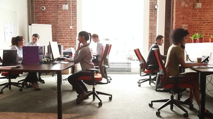 Multi racial office workers working in shared open space room