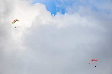 Paragliders floating through clouds and blue sky over Camps Bay, Cape Town.