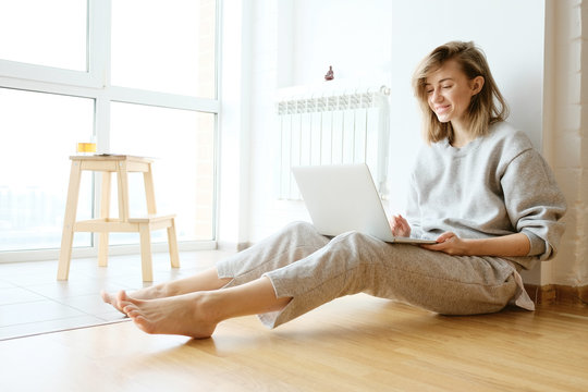 Smiling woman working on laptop in pyjamas