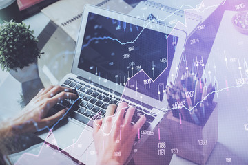 Double exposure of man's hands writing notes of stock market with forex graph background. Concept of research and trading.