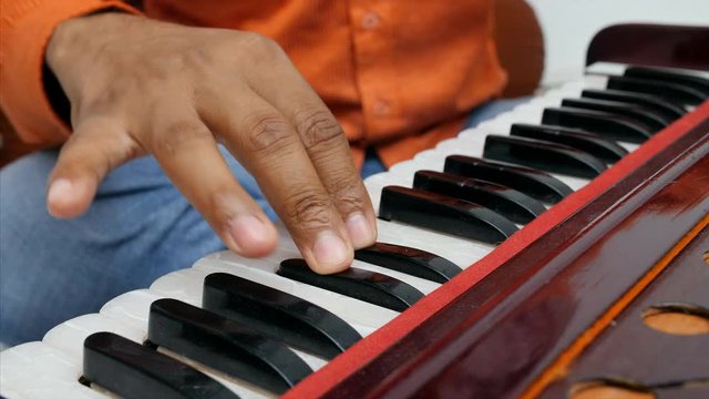 Close up shot of a musician playing Indian traditional musical instrument harmonium . 
