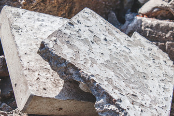 Pile of construction waste gray and old broken concrete pieces lying on a construction site as a textured industrial background.