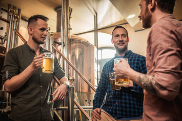 Three men tasting fresh beer in a brewery