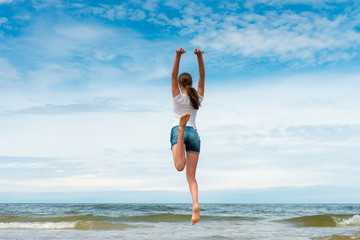 Fototapeta na wymiar Happy girl jumping on the beach at day time