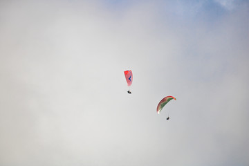 Two paragliders floating through clouds over Camps Bay, Cape Town.