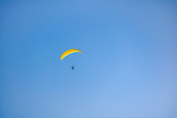 Paraglider floating through a blue sky over Camps Bay, Cape Town.
