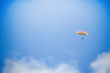 Paraglider floating through a blue sky over Camps Bay, Cape Town.