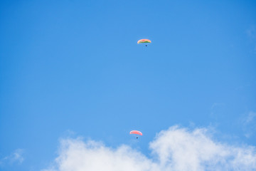 Paraglider floating through a blue sky over Camps Bay, Cape Town.