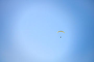 Paraglider floating through a blue sky over Camps Bay, Cape Town.
