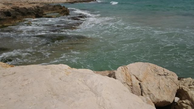 Mediterranean sea waves hitting the rocks on a sunny day
