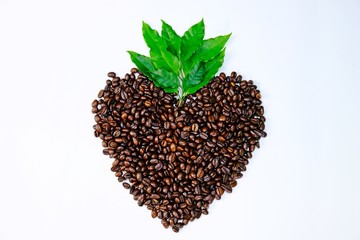 Top view heart-shape roasted coffee beans and green leaves isolate on white background.