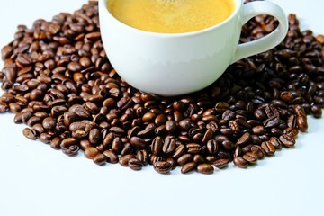 Cropped coffee cup filled with hot coffee surrounded by roasted coffee beans isolate on white background.